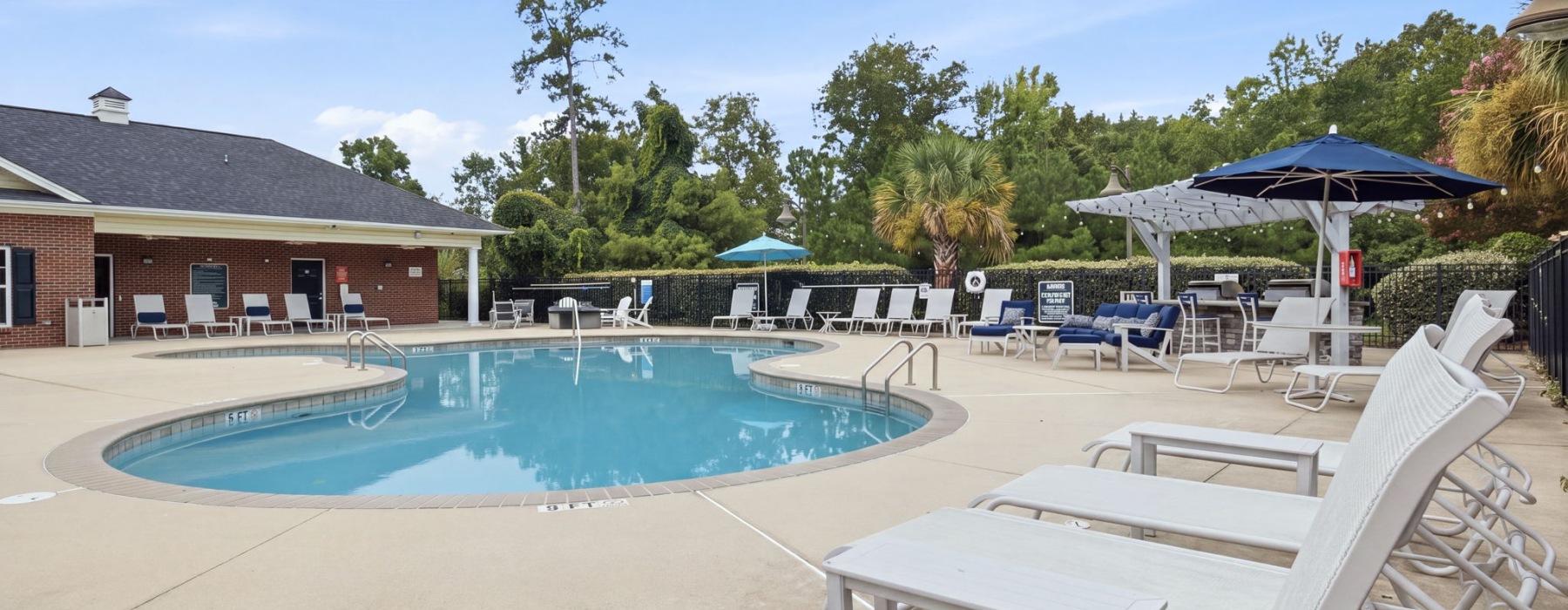 A sparkling pool with lounge chairs and umbrellas at The Summit on 401 apartments in Fayetteville, NC.